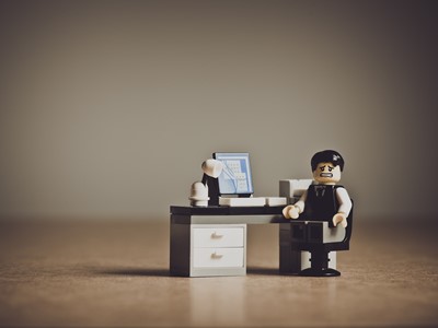 Distressed looking lego mini figure office worker at desk
