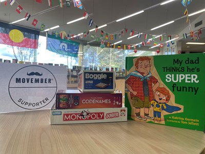 A library display involving some boardgames such as Monopoly, a picture book about Dad's and a Movember poster