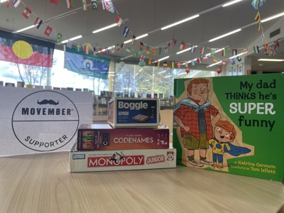 A library display involving some boardgames such as Monopoly, a picture book about Dad's and a Movember poster