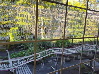 A photo of the large glass windows at Watsonia library. Fleassy Malay's poem is written on the windows in white window marker.
