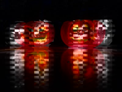 A photo of two carved pumpkins with candles lit inside