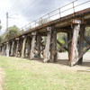 Trestle bridge with wooden beams. Green grass in foreground.