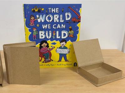 Book, The World We Can Build next to 3 book boxes to demonstrate shape and scale