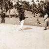 Old image of man taking a put on a sandy hole of a golf course
