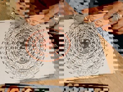 A close up photo of someone colouring in a mandala pattern