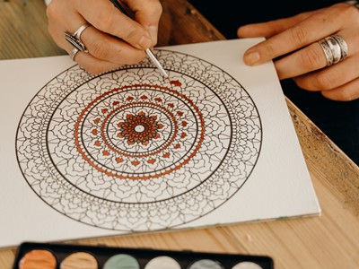 A close up photo of someone colouring in a mandala pattern